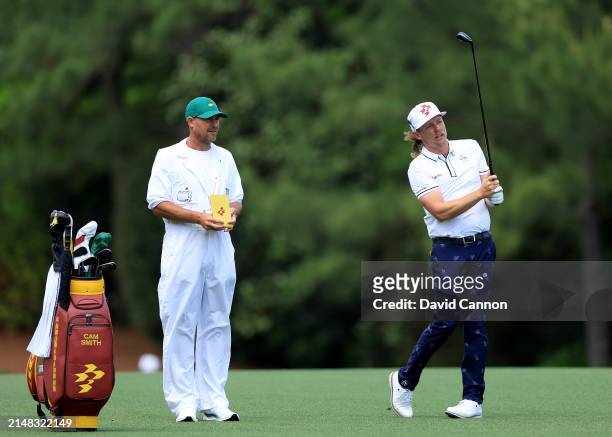 Cameron Smith of Australia prepares to play his second shot on the fifth hole with his caddie during the first round of the 2024 Masters Tournament...