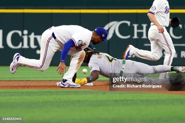 Marcus Semien of the Texas Rangers loses the ball as Lawrence Butler of the Oakland Athletics steals second in the fifth inning at Globe Life Field...