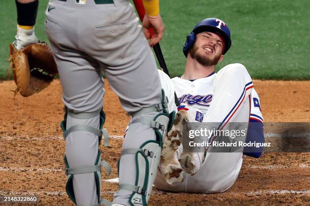 Jonah Heim of the Texas Rangers reacts after being hit by a pitch in the seventh inning against the Oakland Athletics at Globe Life Field on April...