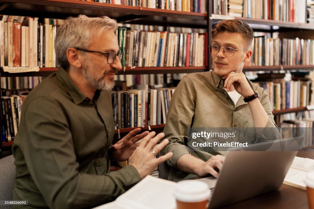College Students Working in Library Being Helped by Tutor