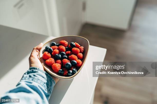 a woman holds a plate of fruits and berries in her hands - red saucer stock pictures, royalty-free photos & images