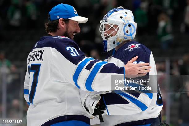 Laurent Brossoit of the Winnipeg Jets is congratulated by Connor Hellebuyck after defeating the Dallas Stars at American Airlines Center on April 11,...