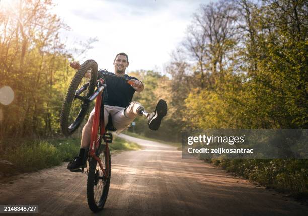 man with a prosthetic leg ride a mountain bike on a hill - acrobatic activity stock pictures, royalty-free photos & images