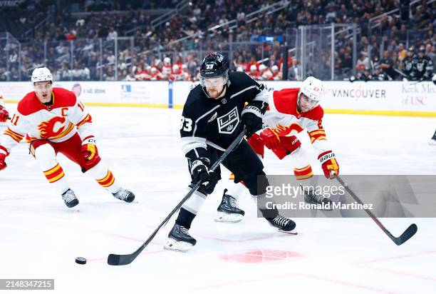 Viktor Arvidsson of the Los Angeles Kings skates the puck against Matt Coronato of the Calgary Flames in the second period at Crypto.com Arena on...