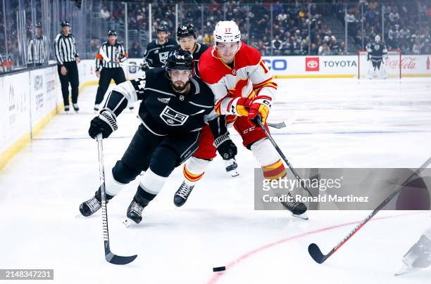 Phillip Danault of the Los Angeles Kings skates the puck against Yegor Sharangovich of the Calgary Flames in the second period at Crypto.com Arena on...