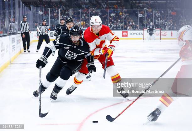 Phillip Danault of the Los Angeles Kings skates the puck against Yegor Sharangovich of the Calgary Flames in the second period at Crypto.com Arena on...