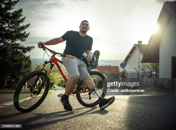 man with a prosthetic leg ride ride a mountain bike in the city - artificial limb stock pictures, royalty-free photos & images