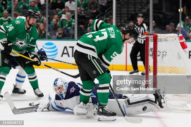 Wyatt Johnston of the Dallas Stars plays the puck next to Laurent Brossoit of the Winnipeg Jets during the first period at American Airlines Center...