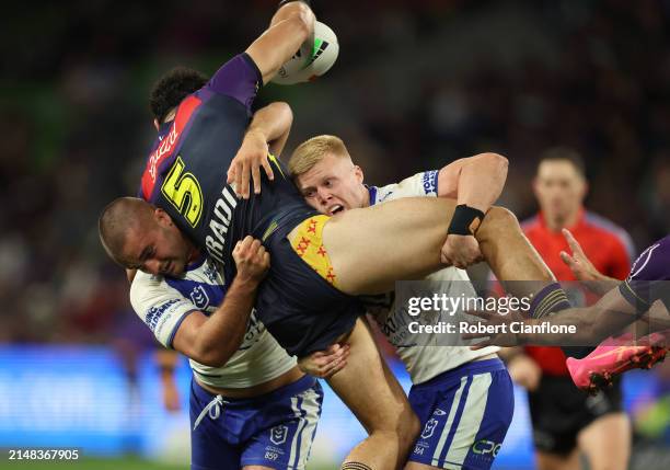 Xavier Coates of the Storm is challenged by Jaeman Salmon and Bailey Hayward of the Bulldogs during the round six NRL match between Melbourne Storm...