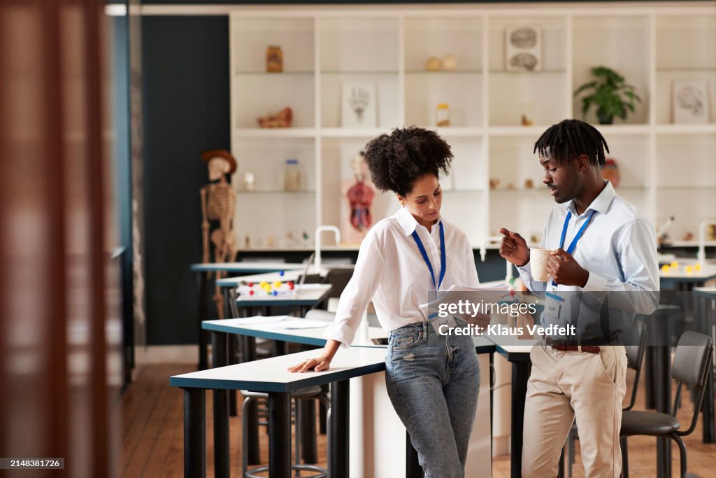 Confident teachers discussing over paper in classroom