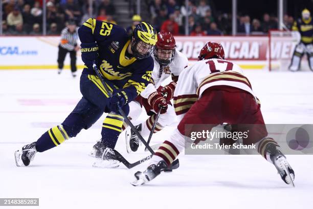 Dylan Duke of the Michigan Wolverines battles Will Smith and Aram Minnetian of the Boston College Eagles for the puck in the second period during the...