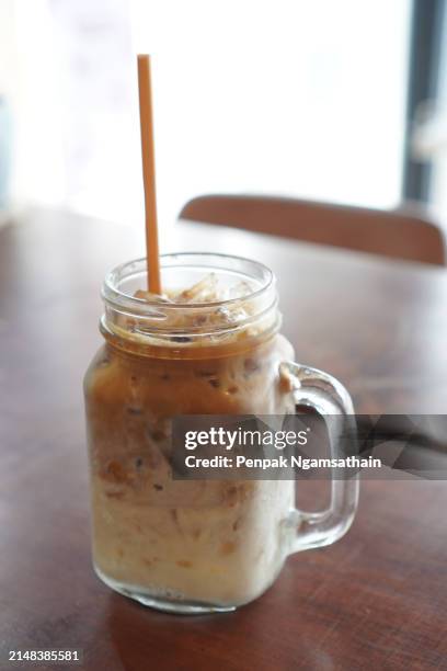 close up view of ice cubes in cold brewed coffee cappuccino in plastic cup put on wooden table blurred background, drink beverage - sugary coffee drink stock pictures, royalty-free photos & images