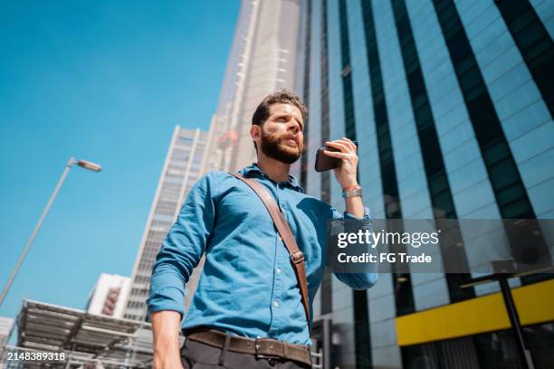 businessman talking on the mobile phone while walking in the street - send sms foto e immagini stock