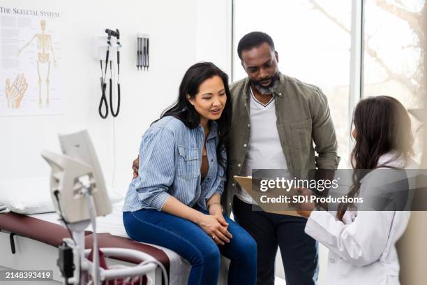 unrecognizable female doctor talks with the couple in her office - human fertility stock pictures, royalty-free photos & images
