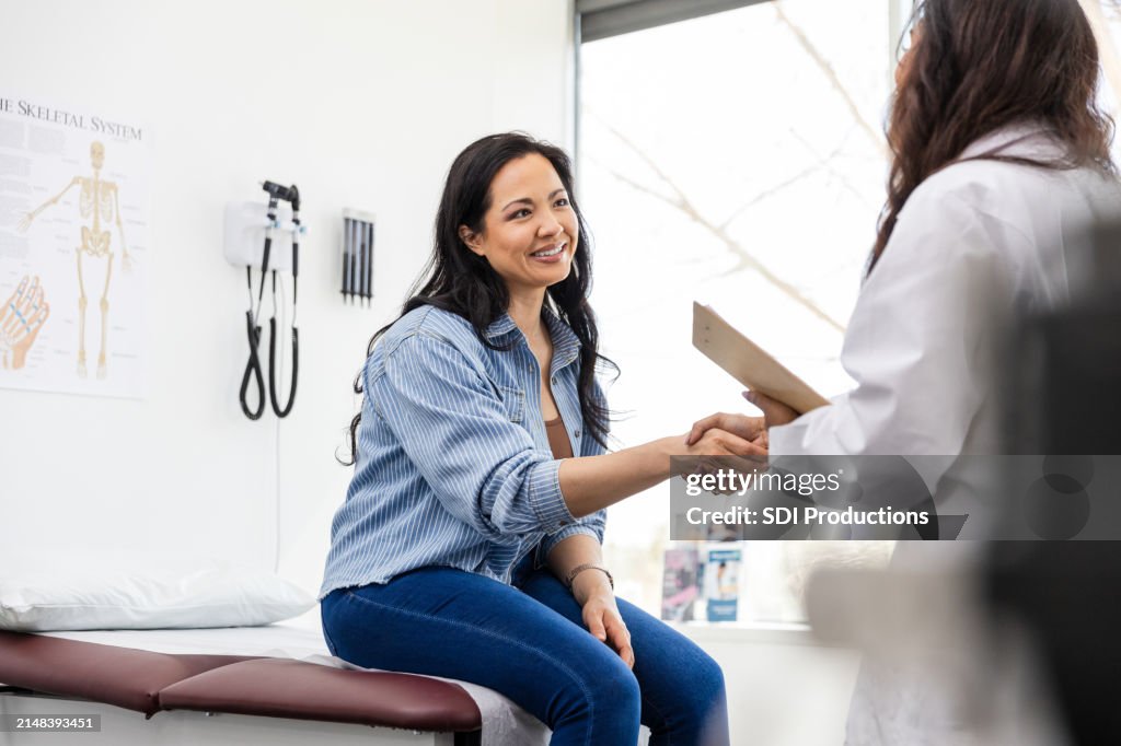 Mid adult female patient shakes hands with her doctor