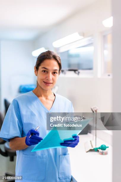 selbstbewusste krankenschwester hält klemmbrett in der klinik - medizinisches-material stock-fotos und bilder