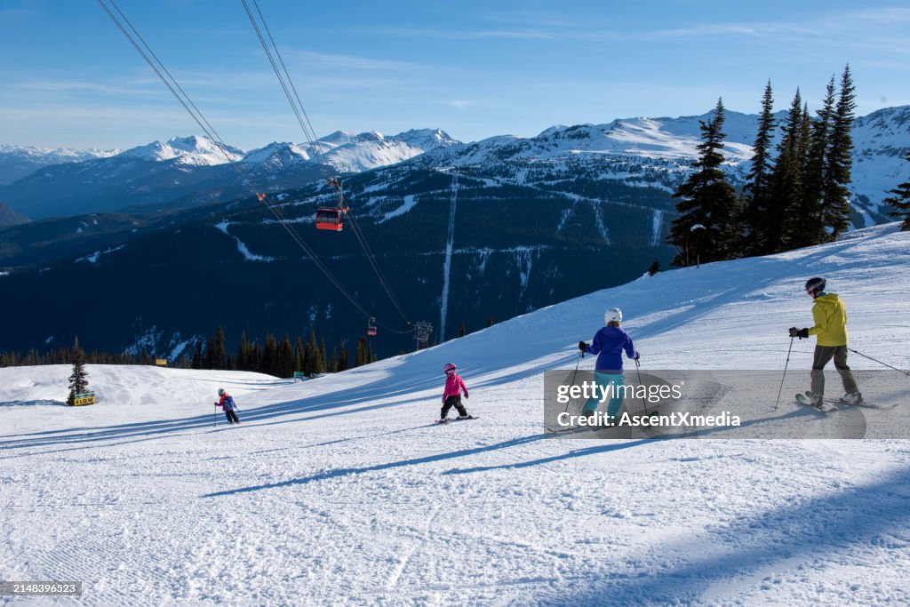 Family skis down slope at ski resort