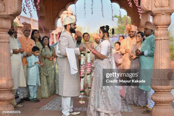 smiling bride and groom ready to exchange floral garlands during their wedding ceremony - wedding stock pictures, royalty-free photos & images