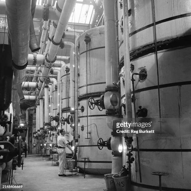 An employee inspects one of the vast evaporating vats at the British Sugar Corporation factory in Bury St Edmunds, Suffolk, England, 1948.