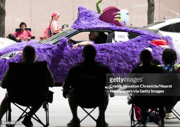 Spectators watch a car covered in purple shag drive by during 36th Annual Houston Art Car Parade on Saturday, April 15, 2023 in Houston.