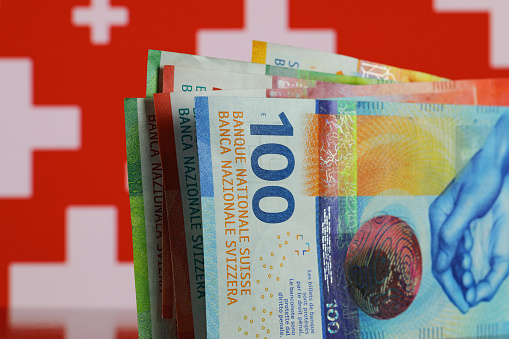 Several banknotes against symbols of the Swiss flag