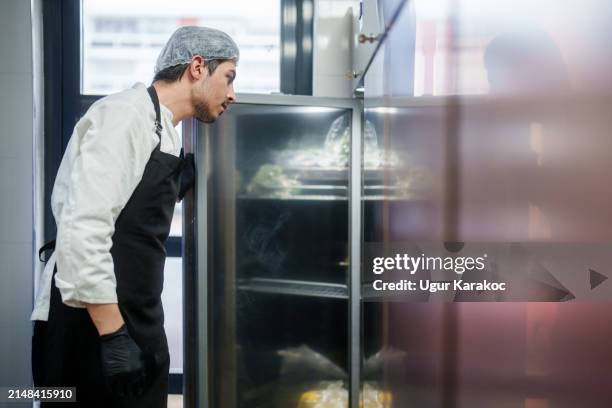 the restaurant chef is checking the refrigerator in the kitchen for ingredients. - restaurant kitchen fridge stock pictures, royalty-free photos & images