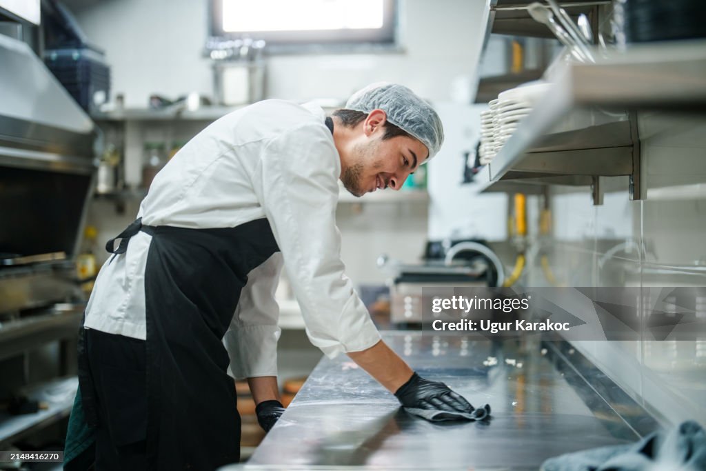 Der Küchenchef wischt die Küchentheke ab.
