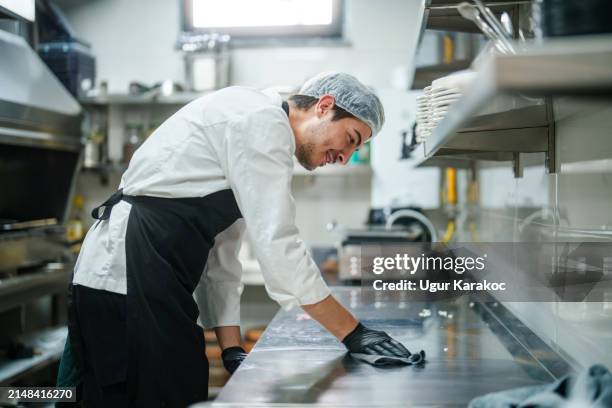 der küchenchef wischt die küchentheke ab. - gastronomieberuf stock-fotos und bilder