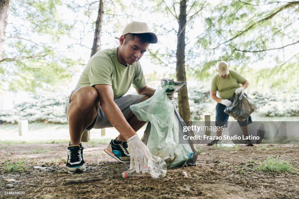 Giovane volontario che raccoglie la spazzatura nel parco pubblico