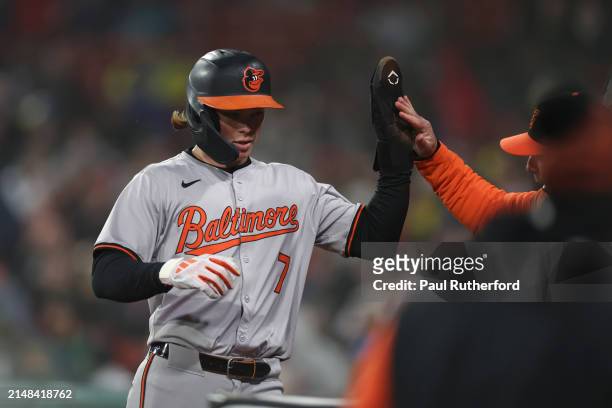 Jackson Holliday of the Baltimore Orioles high fives a coach during the eighth inning against the Boston Red Sox at Fenway Park on April 11, 2024 in...