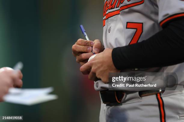 Jackson Holliday of the Baltimore Orioles autographs a baseball before playing against the Boston Red Sox at Fenway Park on April 11, 2024 in Boston,...