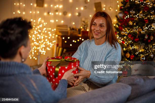 two girlfriends sharing christmas presents - exchanging gifts stock pictures, royalty-free photos & images