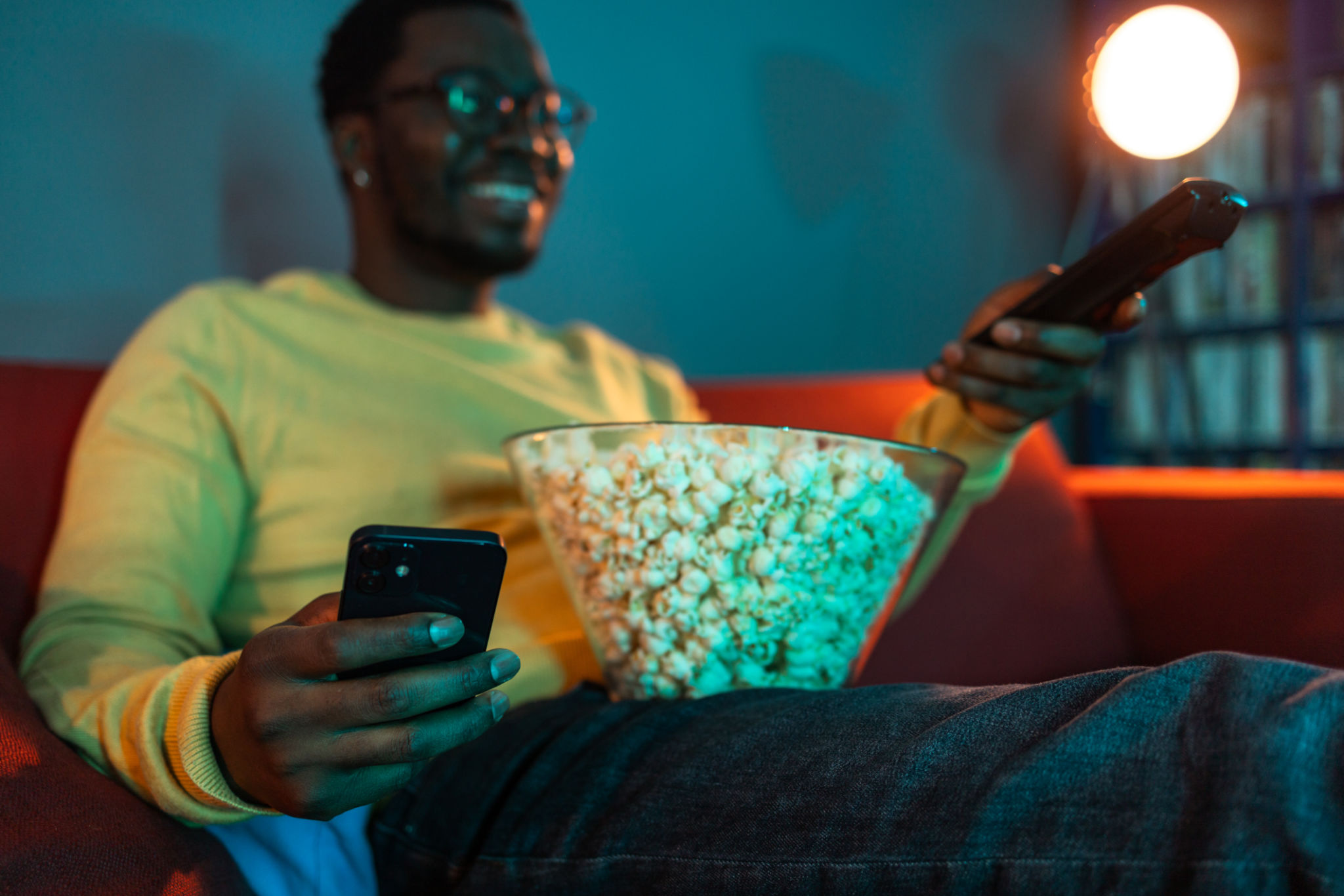 Young man using phone and watching TV at home Young man using phone and watching TV at home