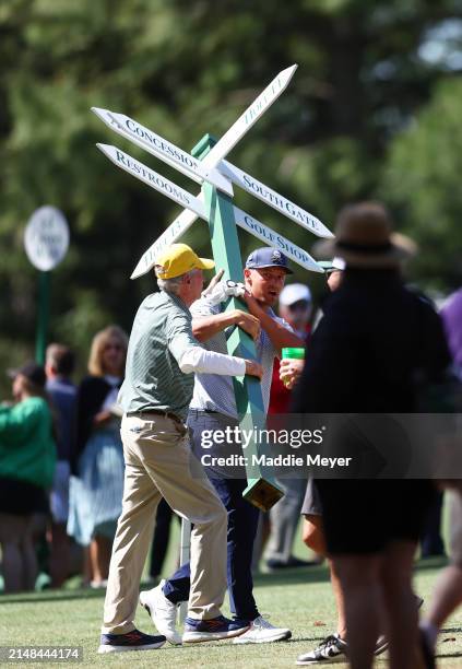 Bryson DeChambeau of the United States moves a sign while preparing to play his second shot on the 13th hole from the 14th fairway during the second...