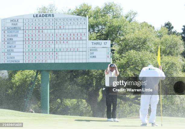 Jason Day of Australia shields his face from the blowing sand on the 18th green during the second round of the 2024 Masters Tournament at Augusta...