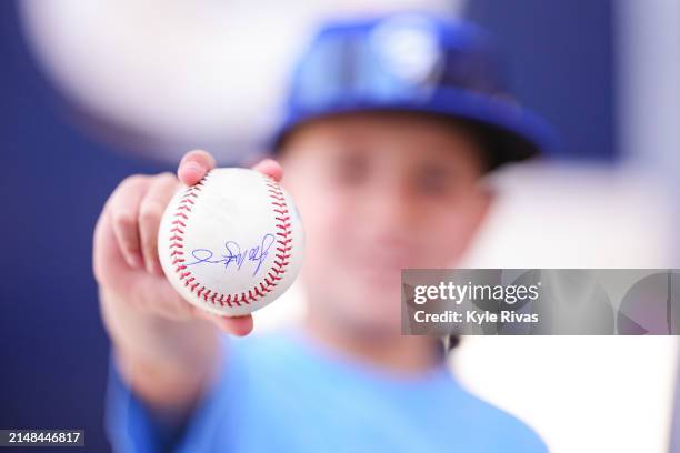 Young fan holds up a signed Kansas City Royals baseball before the game against the Chicago White Sox at Kauffman Stadium on April 6, 2024 in Kansas...