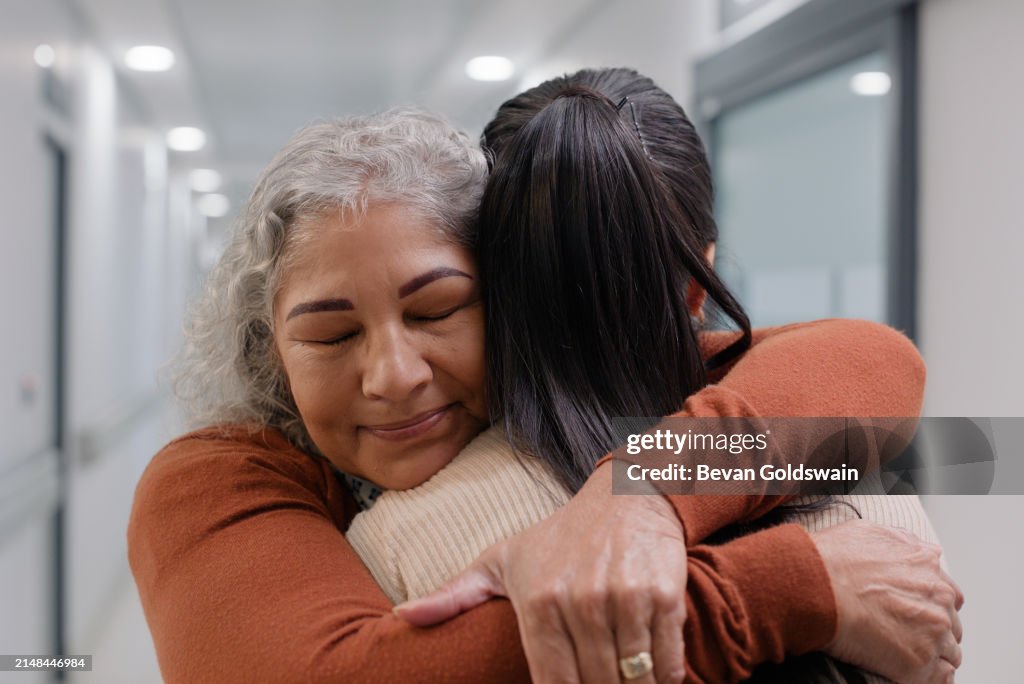 Hug, smile and senior mother with woman in hospital for cancer diagnosis, chemotherapy or treatment. Happy, love and back of female person embracing elderly mom for support, empathy or care in clinic