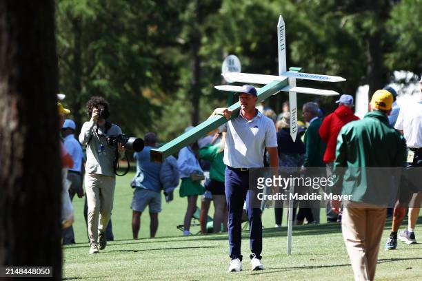 Bryson DeChambeau of the United States moves a sign while preparing to play his second shot on the 13th hole from the 14th fairway during the second...