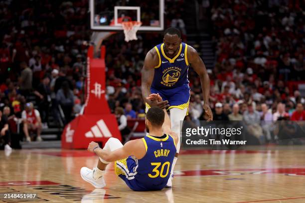 Draymond Green of the Golden State Warriors helps Stephen Curry to his feet in the second half against the Houston Rockets at Toyota Center on April...