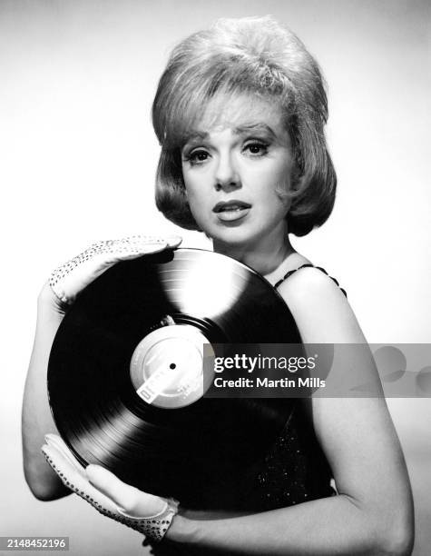 American comedienne, actress, singer and businesswoman, Edie Adams poses for a portrait with a Decca vinyl record, Los Angeles, California, circa...