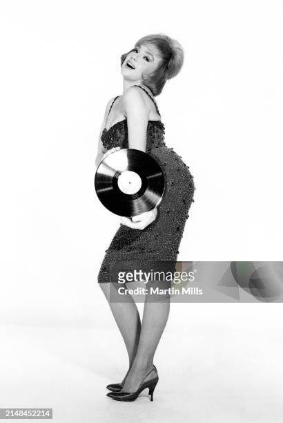 American comedienne, actress, singer and businesswoman, Edie Adams poses for a portrait with a Decca vinyl record, Los Angeles, California, circa...