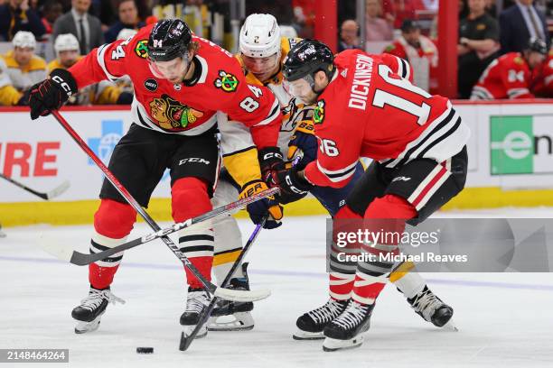 Landon Slaggert and Jason Dickinson of the Chicago Blackhawks battle with Luke Schenn of the Nashville Predators for control of the puck during the...