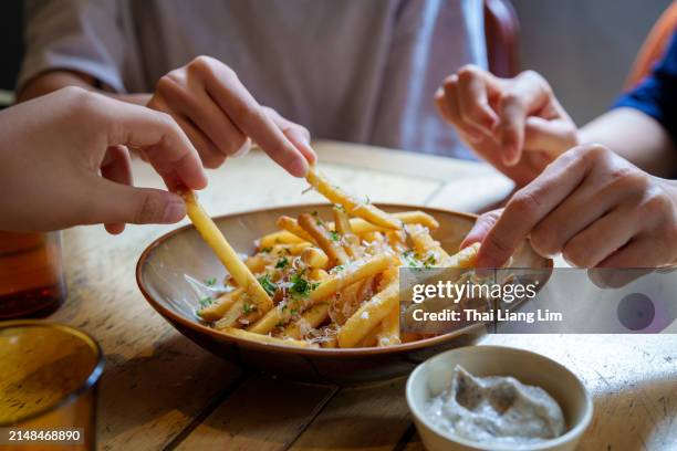 friends sharing and enjoying fries topped with parmesan cheese and truffled mayonnaise sauce. - batata-frita-lanche imagens e fotografias de stock