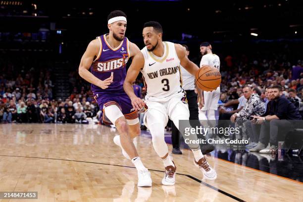 McCollum of the New Orleans Pelicans drives against Devin Booker of the Phoenix Suns during the game at Footprint Center on April 07, 2024 in...