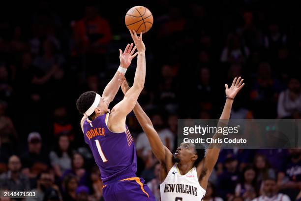 Devin Booker of the Phoenix Suns attempts a shot over Herbert Jones of the New Orleans Pelicans during the game at Footprint Center on April 07, 2024...