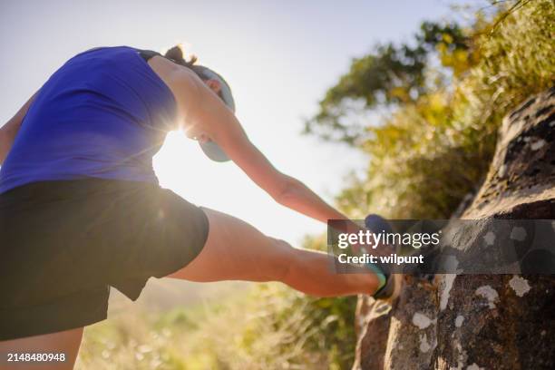 female fell runner stretching hamstring in outdoors setting trail run at sunset - hamstring stretch stock pictures, royalty-free photos & images