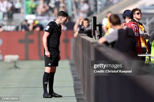 Referee Florian Badstubner reviews the Video Assistant Referee monitor during the Bundesliga match between Borussia Mönchengladbach and Borussia...
