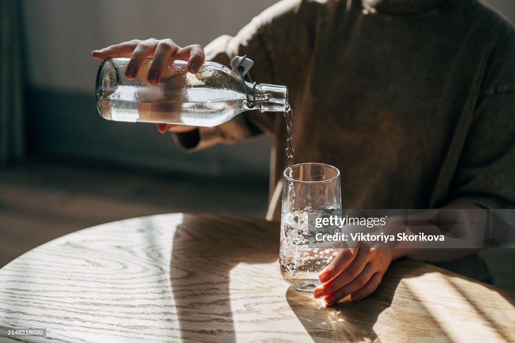 A woman at the table pours a glass of water from a bottle
