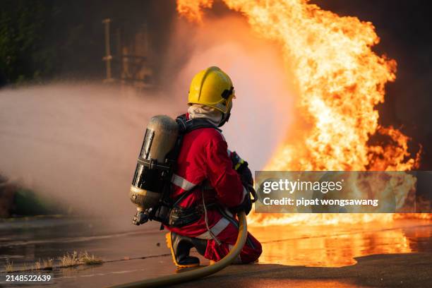 firefighters' nighttime fire suppression training by simulating fire control in industrial plants with gas pipelines or oil pipelines, conducted by a teamwork. - planta petroquímica fotografías e imágenes de stock