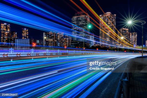 busy light trails against urban city at night - lichtspur stock-fotos und bilder